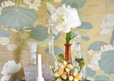 a bottle tray with flowers in front of a water lily wallpaper in a dining room designed by Brand*Eye Home