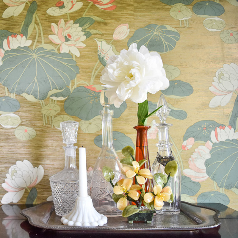 a bottle tray with flowers in front of a water lily wallpaper in a dining room designed by Brand*Eye Home