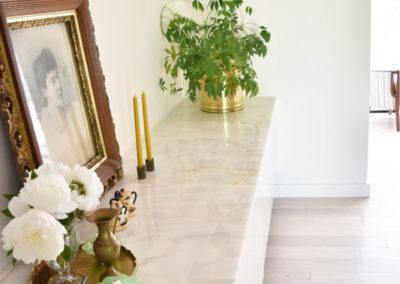a marble counter with framed photo, flowers, and tall candles along the side of a dining room designed by Brand*Eye Home
