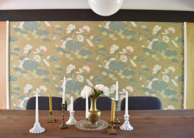 a collection of candles on a wood dining table in front of water lily wallpaper in a dining room designed by Brand*Eye Home