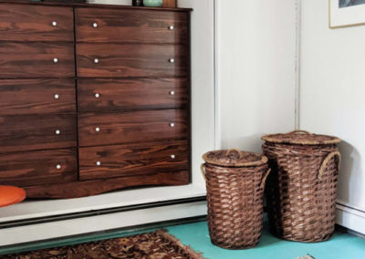 decorative rugs, wicker hampers, and a dresser nook in a dressing room designed by Brand*Eye Home