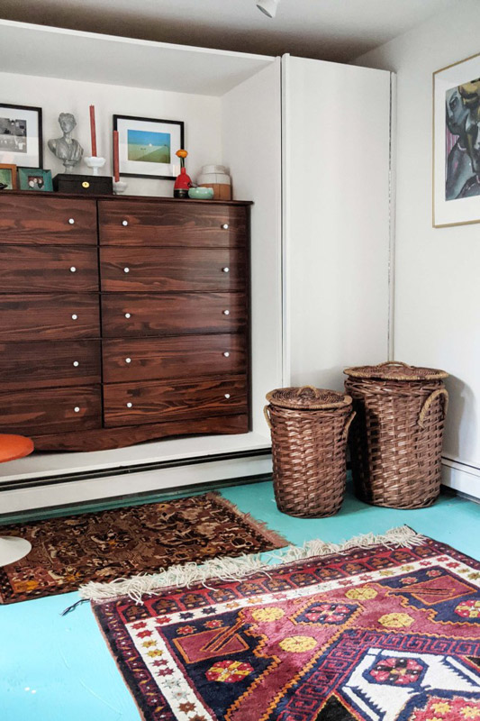 decorative rugs, wicker hampers, and a dresser nook in a dressing room designed by Brand*Eye Home