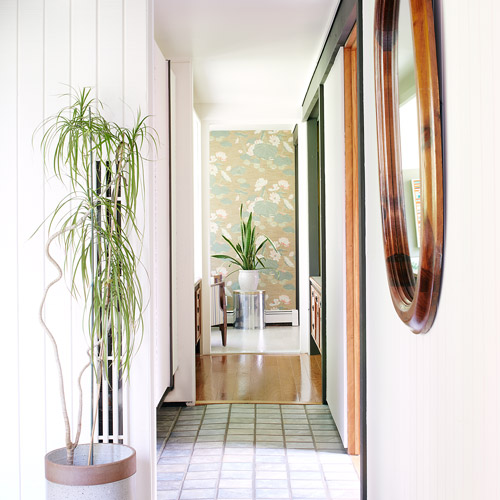 a brightly lit entry hallway with mirror and potted plants designed by Brand*Eye Home
