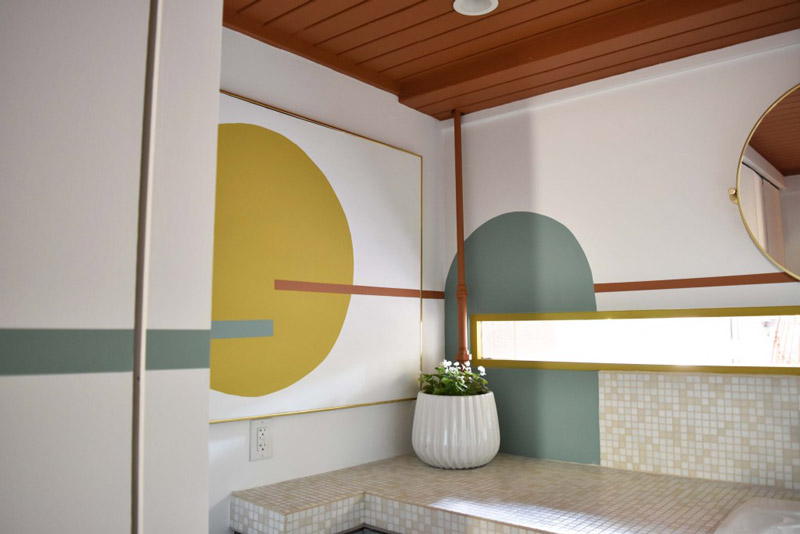 the corner of a bathroom designed by Brand*Eye, featuring a framed mural and potted plant