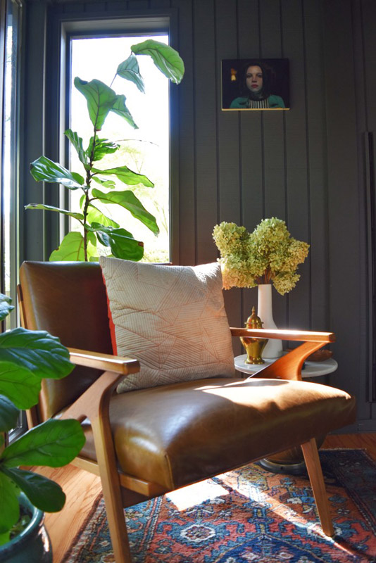 close-up of a leather-cushion midcentury modern chair in a reading nook designed by Brand*Eye Home