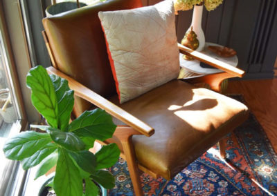 overhead shot of a chair between potted plants with a small side table in a reading nook designed by Brand*Eye Home