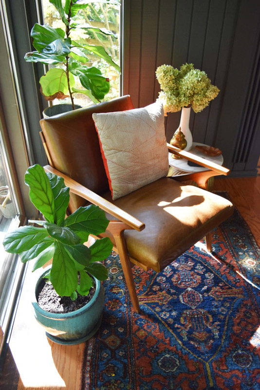 overhead shot of a chair between potted plants with a small side table in a reading nook designed by Brand*Eye Home