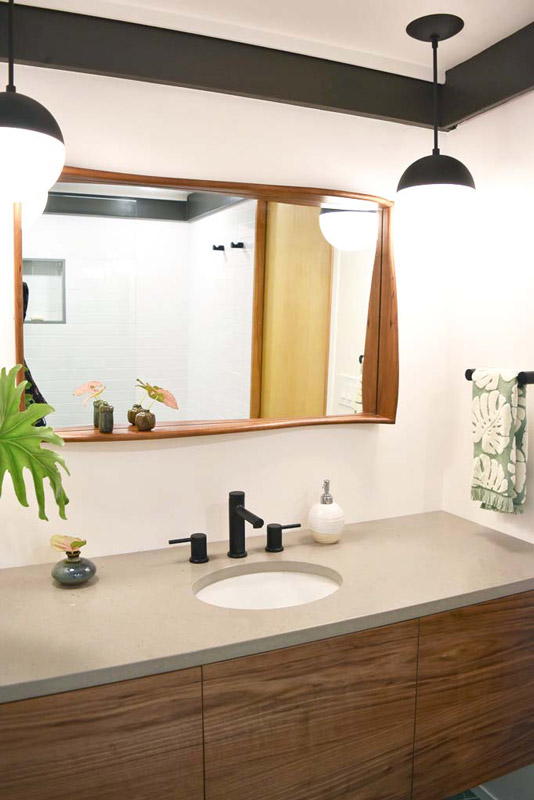 the counter with large wood framed mirror in a bathroom designed by Brand*Eye Home