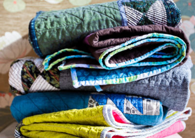 a folded stack of Brand*Eye Home custom quilts