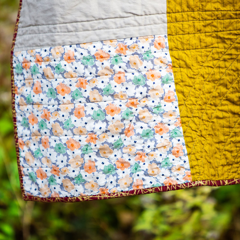 a mustard, white, and floral patterned custom handmade quilt from Brand*Eye Home