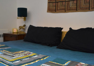 a bed dressed with a handmade patterned blue quilt from Brand*Eye Home