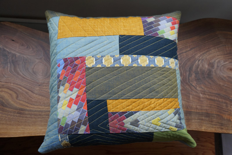 a patchwork, multi-patterned quilt pillow handmade by Brand*Eye Home