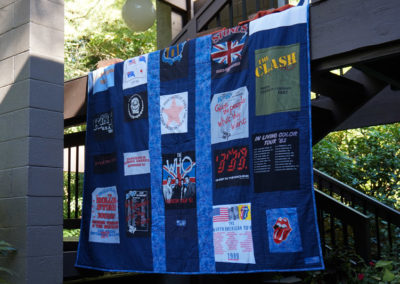 a large quilt featuring band poster patterns, handmade by Brand*Eye Home